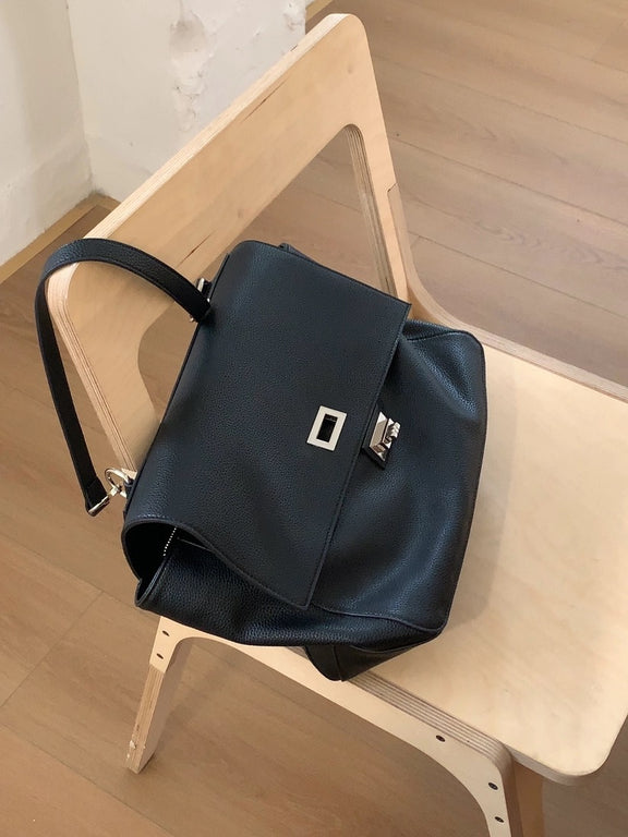 Black handbag with a silver clasp on a wooden chair
