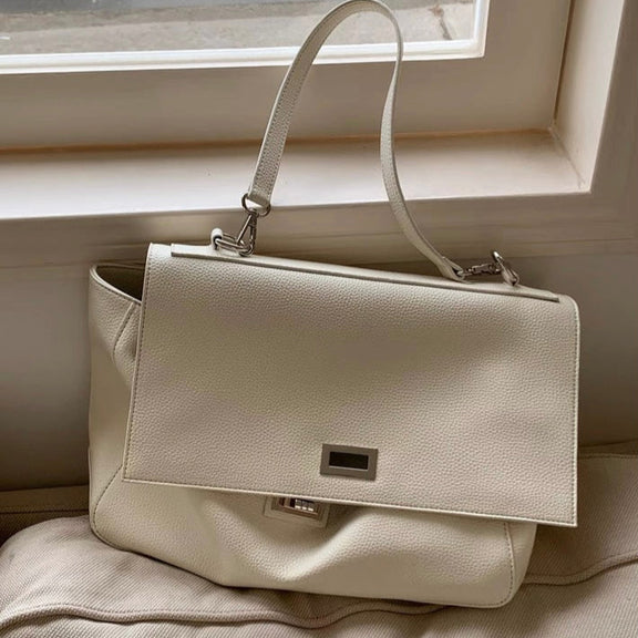 Beige handbag on a light-colored surface with a neutral background