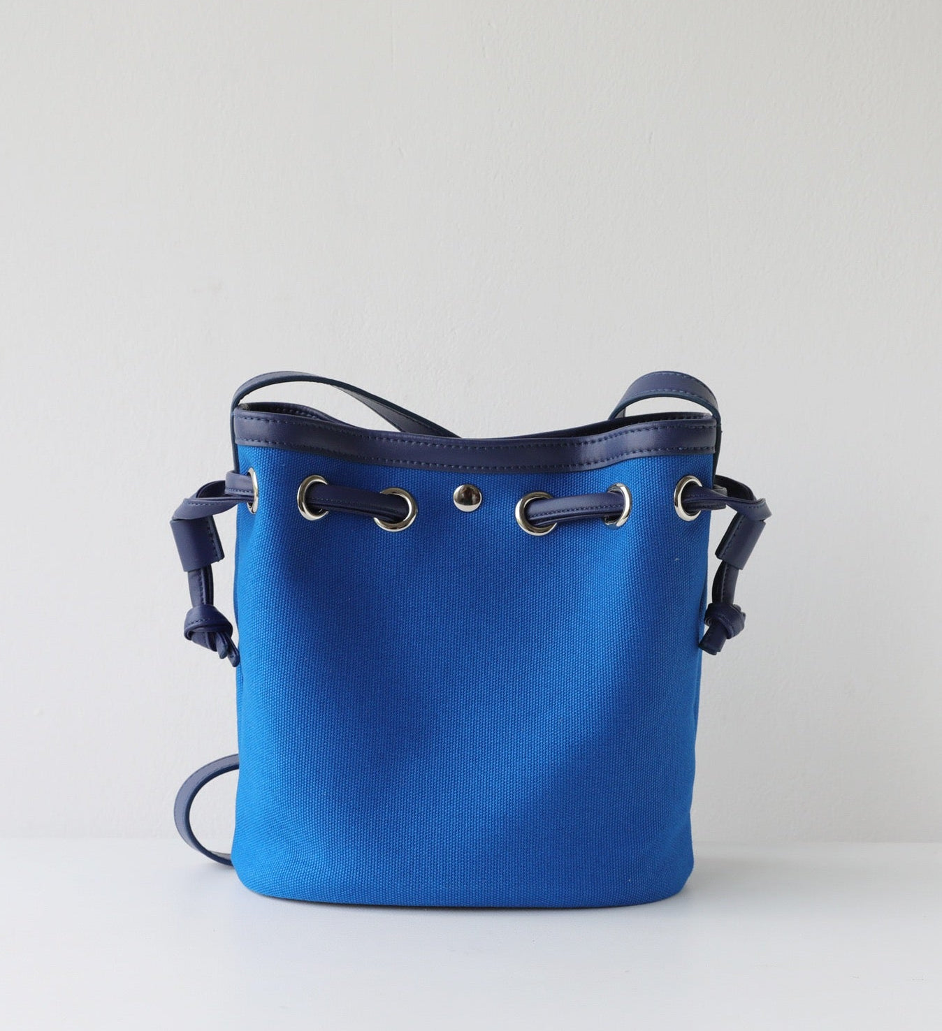 Blue bucket bag with drawstring on a light gray background
