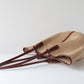 Woven bag with brown handles on a white background