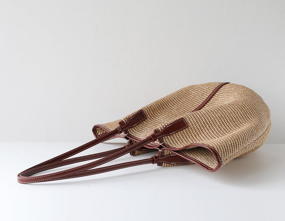Woven bag with brown handles on a white background