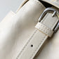 Close-up of a white leather bag with a silver buckle on a light gray background