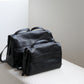 Black leather bag on a white surface with a neutral background