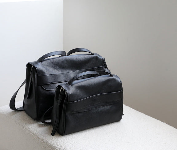 Black leather bag on a white surface with a neutral background