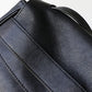 Close-up of a black leather bag with visible stitching on a light gray background