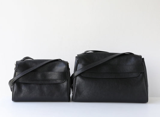 Two black leather handbags on a white background
