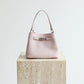 Pink handbag on a wooden block with 'Shevennie Studio' branding.