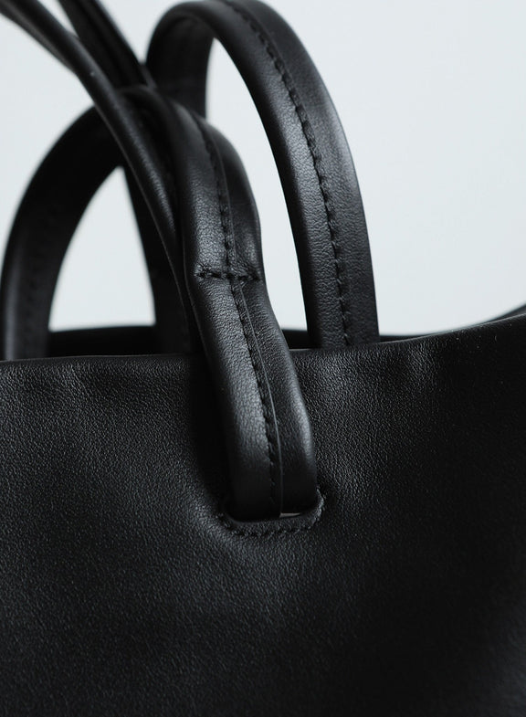 Close-up of a black leather handbag with handles.