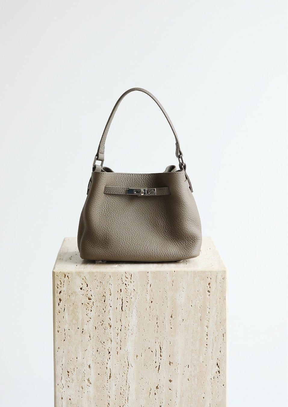Gray handbag on a stone surface with 'Shevennie Studio' branding.