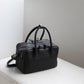 Black handbag on a light gray surface with a neutral background