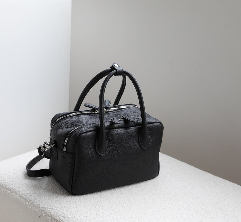 Black handbag on a light gray surface with a neutral background