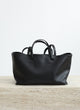 Black leather handbag on a light wooden surface with a white background