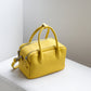 Yellow handbag on a white surface with a neutral background