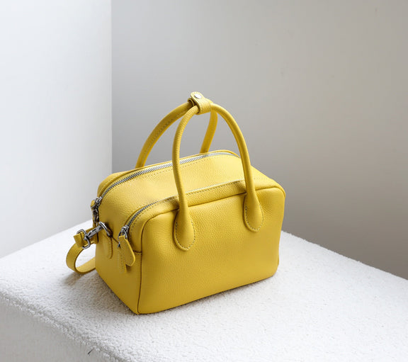 Yellow handbag on a white surface with a neutral background