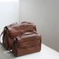Brown leather bag on a light gray surface with a neutral background