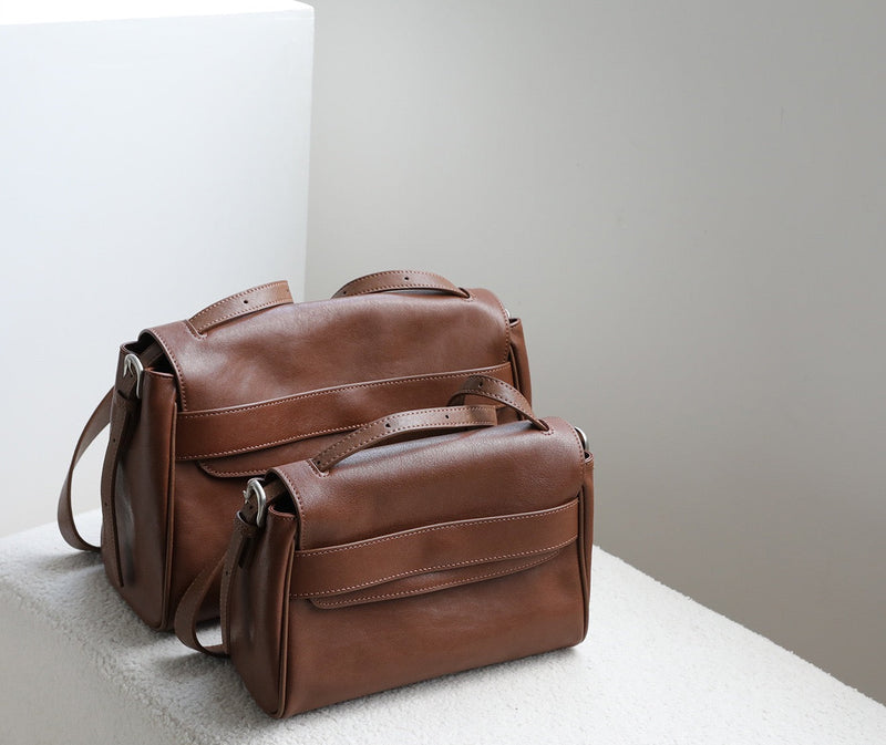 Brown leather bag on a light gray surface with a neutral background