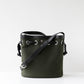 Green bucket bag with black leather strap on a white background