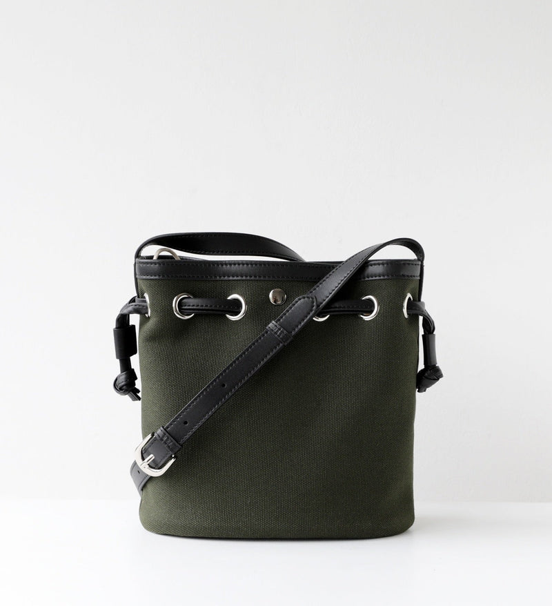 Green bucket bag with black leather strap on a white background