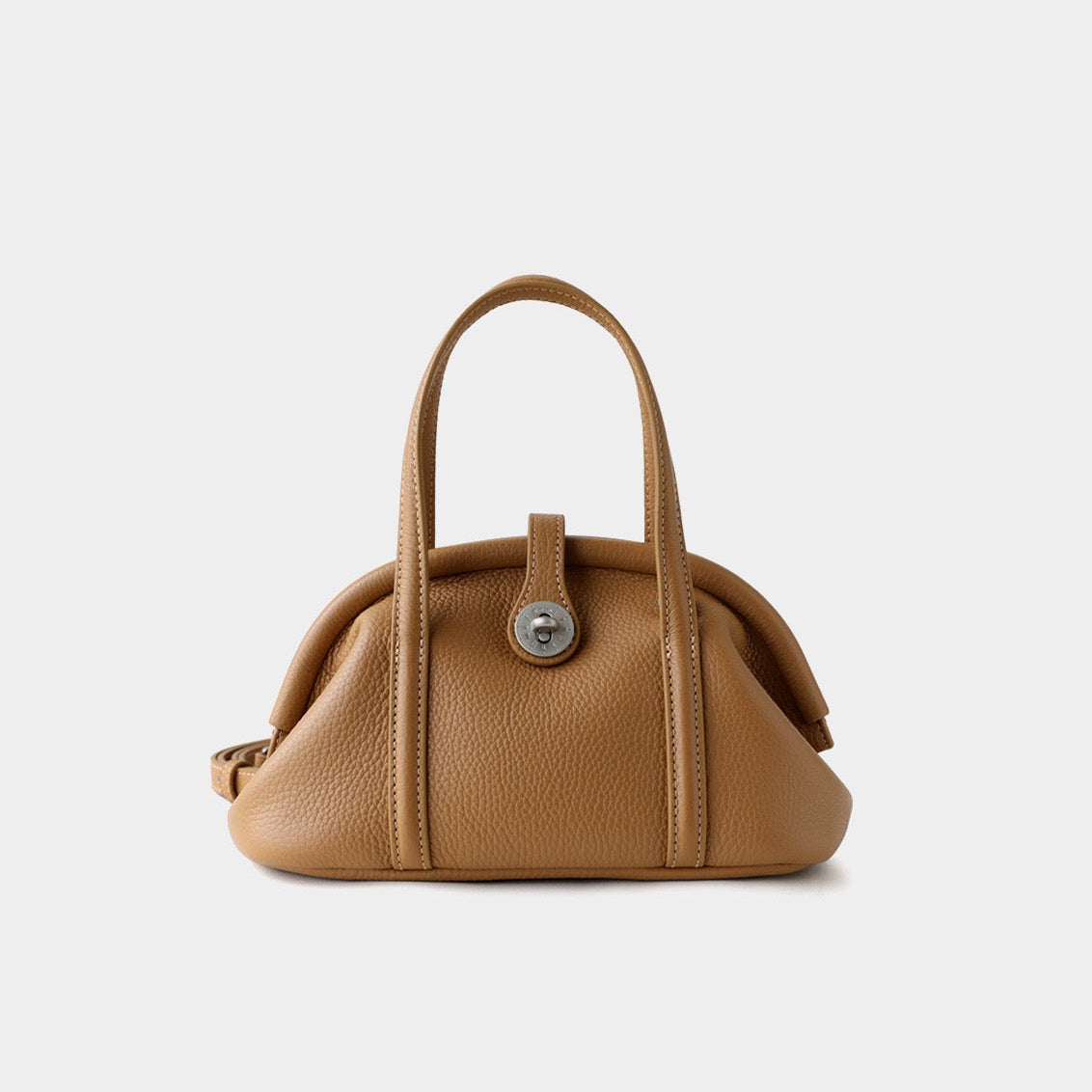 Tan leather handbag with a silver clasp on a light gray background