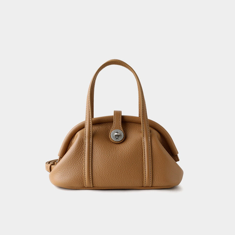 Tan leather handbag with a silver clasp on a light gray background