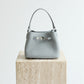 Gray handbag on a wooden block with 'Shevennie Studio' branding.