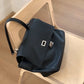 Black handbag with a silver clasp on a wooden chair