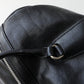 Close-up of a black leather bag with a zipper detail on a light gray background