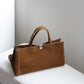 Brown leather tote bag on a white surface with a light gray background