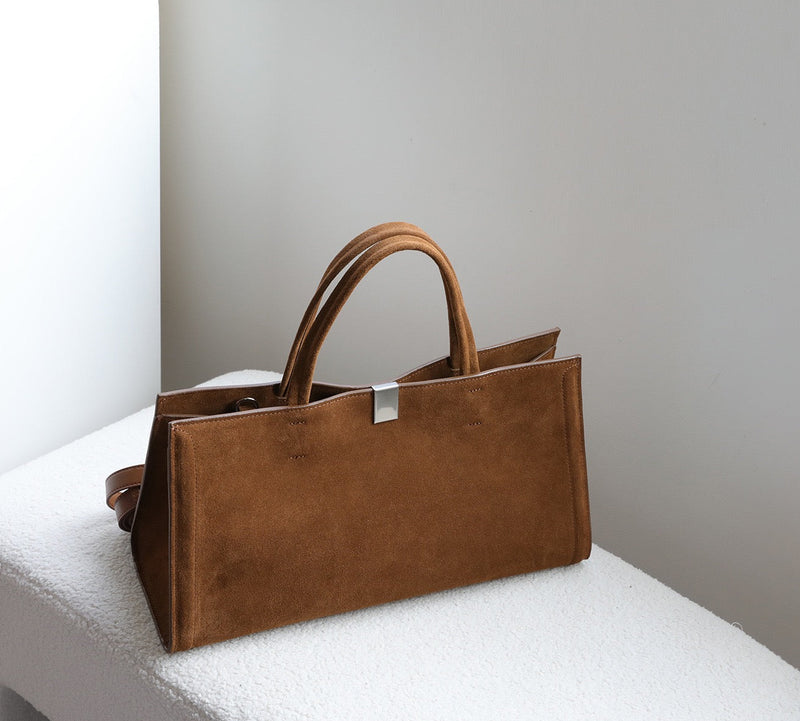 Brown leather tote bag on a white surface with a light gray background