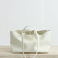 White leather tote bag on a wooden surface with a light gray background