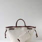 Beige tote bag with brown handles and trim on a light gray background