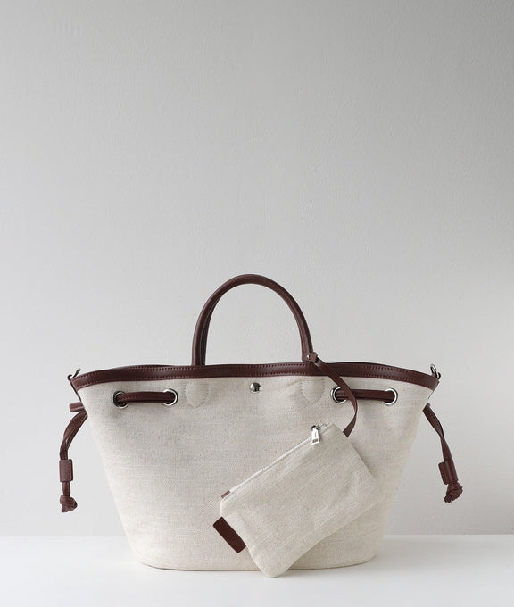 Beige tote bag with brown handles and trim on a light gray background