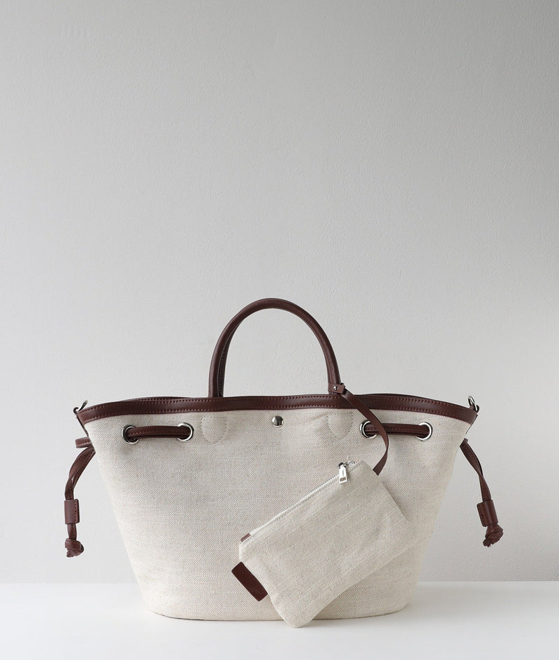 Beige tote bag with brown handles and trim on a light gray background