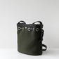 Green bucket bag with black straps on a light gray background