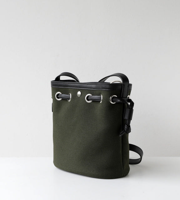 Green bucket bag with black straps on a light gray background