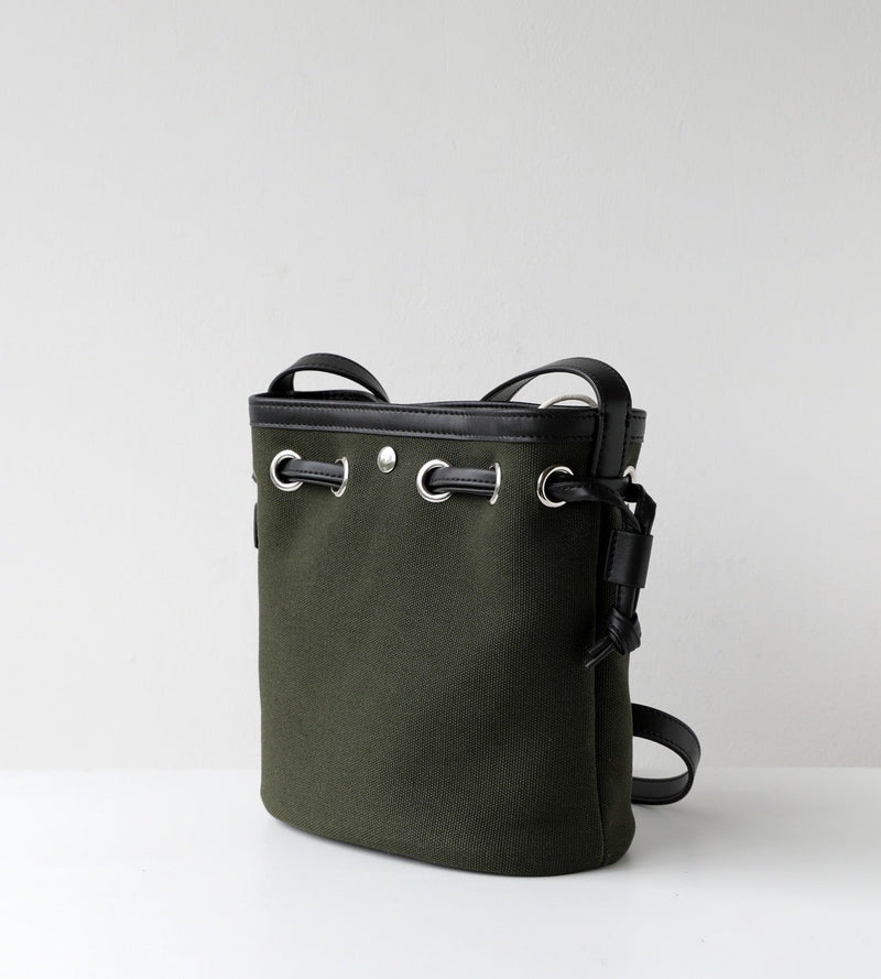Green bucket bag with black straps on a light gray background