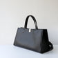 Black handbag on a light gray background