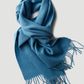Blue wool scarf with fringes on a light gray background