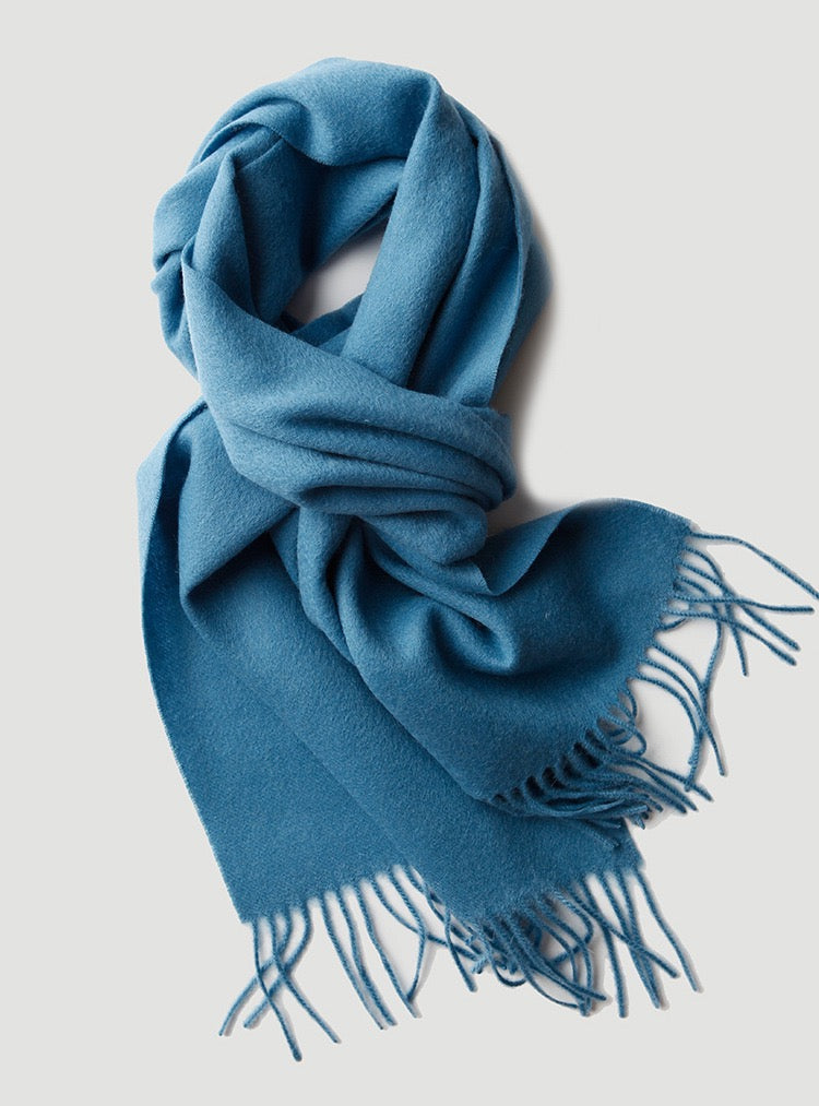 Blue wool scarf with fringes on a light gray background
