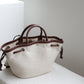 White tote bag with brown handles and accents on a light surface.