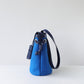 Blue handbag with a black strap on a white background