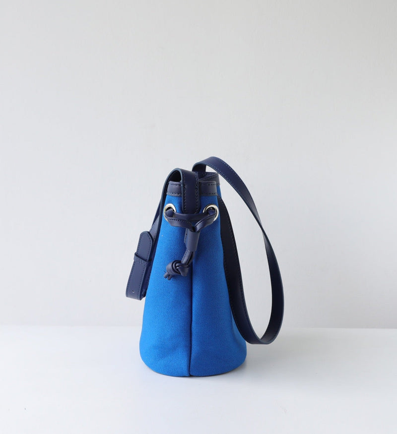 Blue handbag with a black strap on a white background