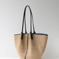Woven handbag with black straps on a light gray background