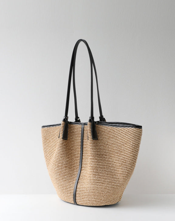 Woven handbag with black straps on a light gray background