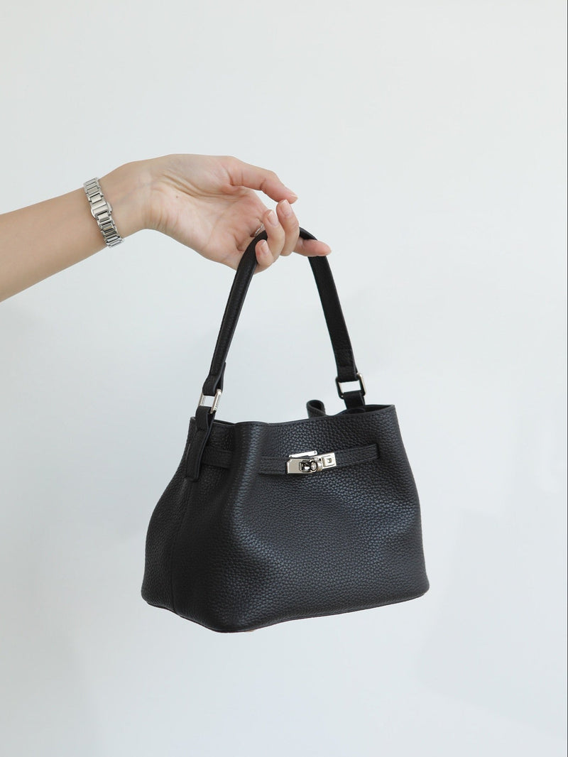 Black handbag held by a hand on a white background