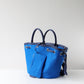 Blue handbag with black handles on a light gray background