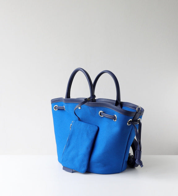 Blue handbag with black handles on a light gray background