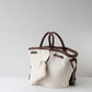 Canvas handbag with brown leather handles and accents on a light gray background