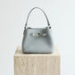 Gray handbag on a wooden block with 'Shevennie Studio' branding.