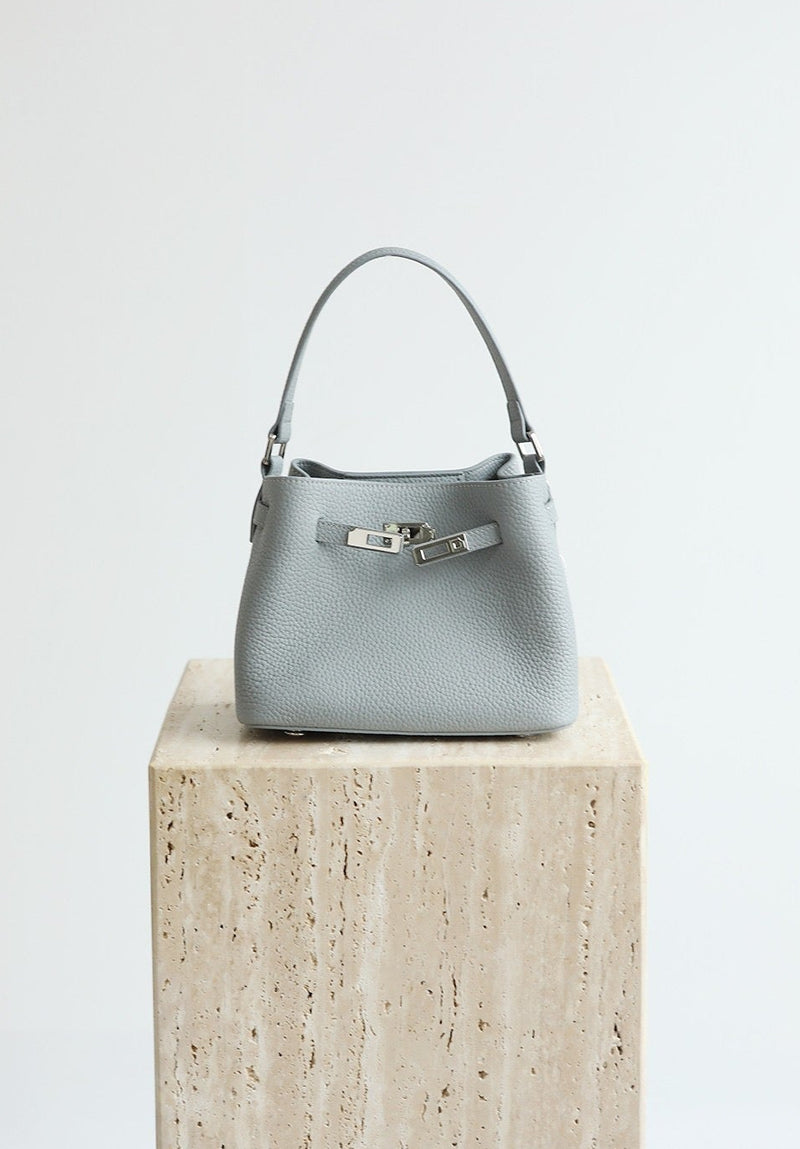 Gray handbag on a wooden block with 'Shevennie Studio' branding.